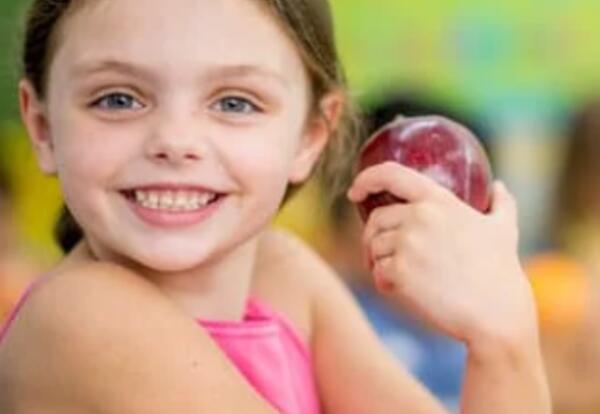 Little girl holding an apple.