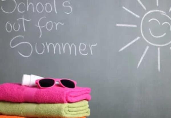 Chalk board with a smiling sun, three colorful beach towels and the phrase School's Out for the Summer